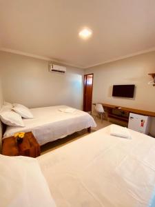 a hotel room with two beds and a flat screen tv at Bella Spiaggia Suítes in Flecheiras