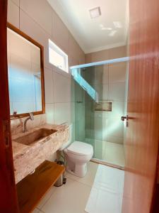 a bathroom with a sink and a toilet and a mirror at Bella Spiaggia Suítes in Flecheiras