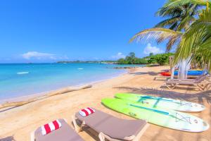 a beach with two chairs and a surfboard on it at Luxe Beach Resort in Discovery Bay