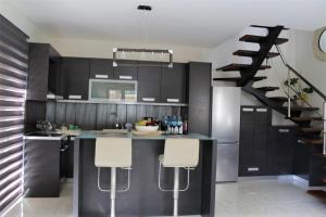 a kitchen with black cabinets and a kitchen island with white stools at Casa Ariadne in Plataniás