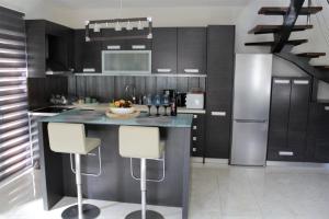 a kitchen with black cabinets and a island with bar stools at Casa Ariadne in Plataniás