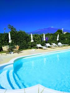 a swimming pool with chairs and umbrellas next to at Case Vacanze Residence Trinacria in Acireale