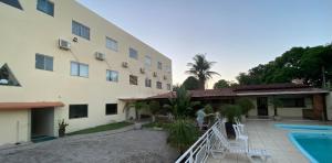 a man standing next to a building with a pool at Hotel Santana - Posto da Mata BA in Pasto da Mata