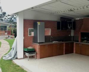 a kitchen with a refrigerator and a brick wall at Estadia independiente en el campo Boyacense in Duitama