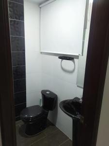 een badkamer met een zwart toilet en een wastafel bij Estadia independiente en el campo Boyacense in Duitama