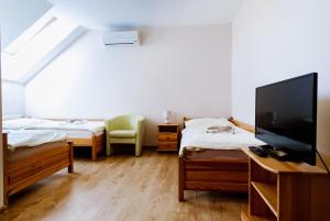 a room with two beds and a flat screen tv at Penzión Vendelín in Veľké Zálužie