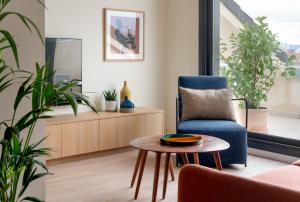 uma sala de estar com uma cadeira azul e uma mesa em Apartahotel Líbere Vitoria em Vitoria-Gasteiz
