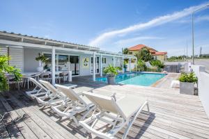 una terraza con sillas, una mesa y una piscina en Villa Vermaire Apartments, en Willemstad