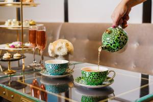 a person is pouring tea into cups on a table at Four Seasons Hotel One Dalton Street, Boston in Boston