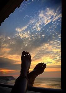 a person laying on a window sill with their feet up at Surf House Chicama in Puerto Chicama