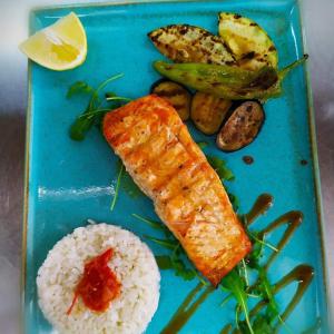 a blue plate with rice and a piece of fish and vegetables at The Wave in Sidari