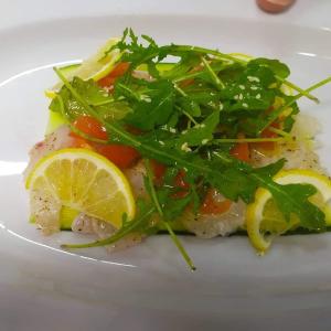 a plate of food with fish with vegetables and lemon slices at The Wave in Sidari