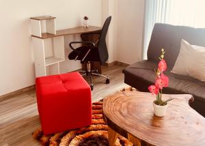 a living room with a red ottoman and a table at Apartamento zona colonial lindísimo (102) in Zipaquirá