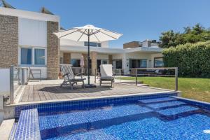 una piscina con 2 sillas y una sombrilla junto a una casa en Luxury Beachfront Villa, en Colares