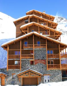 un grand bâtiment en bois avec de la neige devant lui dans l'établissement Chalet des Neiges Plein Sud, à Val Thorens