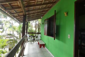 a green house with a porch with a butterfly on the wall at Pousada Jambo Trindade in Trindade