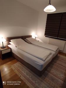 a bed in a bedroom with two lamps and a window at Apartman SL Bjelasnica in Sarajevo