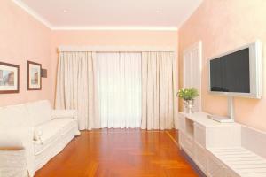 ein Wohnzimmer mit einem weißen Sofa und einem Flachbild-TV in der Unterkunft Colosseo Studio Suite in Rom