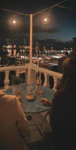 een vrouw die 's nachts aan een tafel op een balkon zit bij Casa Vista Marina in Ponta Delgada