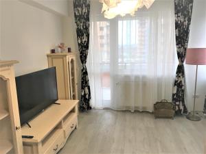 ein Wohnzimmer mit einem TV auf einer Kommode und einem Fenster in der Unterkunft 23 Residence in Braşov
