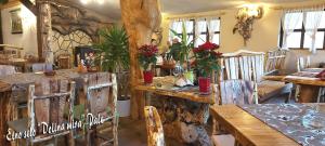 a dining room with wooden tables and chairs and a tree at Apartman Romanija Dolina mira in Pale +5 photos