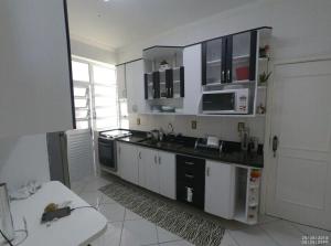 uma cozinha com armários brancos e um forno com placa de fogão em Apartamento Alto padrão de Frente para o mar no Guarujá