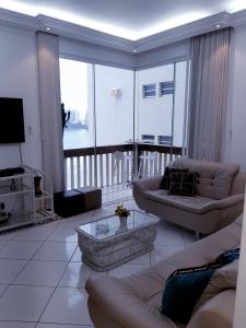 uma sala de estar com um sofá e uma televisão em Apartamento Alto padrão de Frente para o mar no Guarujá