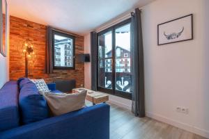 - un salon avec un canapé bleu et une grande fenêtre dans l'établissement Appartement Cham-Vue, à Chamonix-Mont-Blanc