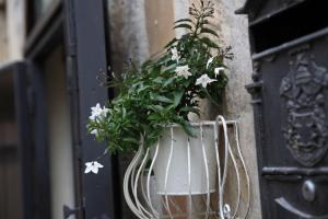 Un jarrón blanco con flores colgando de una puerta en La Neviera nei Sassi, en Matera