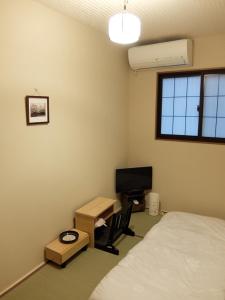 a bedroom with a bed and a desk and a television at Guesthouse Engawa in Kyoto