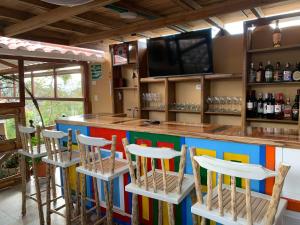 a bar with colorful bar stools and a flat screen tv at La Estancia Hotel Boutique in Salamina