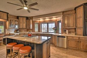 a kitchen with wooden cabinets and a large island with bar stools at Hot Tub, Grill Hilltop Log Cabin in Hot Springs! in Hot Springs