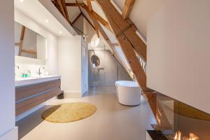 an attic bathroom with a sink and a tub at Bossche Suites Stationsweg in Den Bosch
