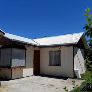 a small white house with a garage at Cabaña centro Pitrufquen in Pitrufquén