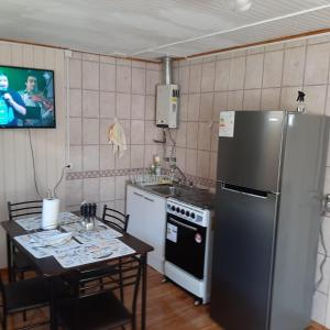 eine Küche mit einem Kühlschrank und einem Tisch mit Stühlen in der Unterkunft Cabaña centro Pitrufquen in Pitrufquén