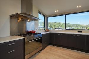 a kitchen with a stove and a large window at Bliss on the Bay in Kaikoura