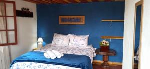 a blue bedroom with a bed with towels on it at Pousada Esquina de Lavras in Lavras Novas