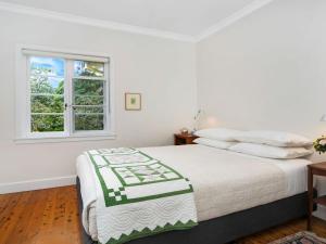 a white bedroom with a bed and a window at Canary Cottage in Bowral