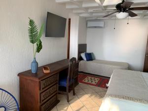 a room with a desk and a bedroom with a bed at El Encanto Casa Boutique in Manzanillo