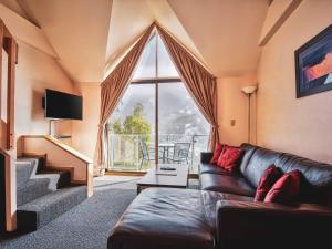 a living room with a couch and a large window at Lantern 1 Bedroom Loft with car space and Majestic View in Thredbo