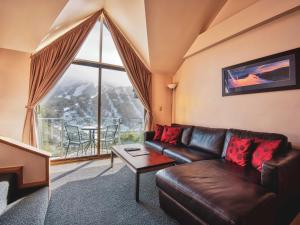 a living room with a leather couch and a large window at Lantern 1 Bedroom Loft with car space and Majestic View in Thredbo