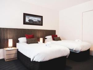 two beds in a room with white and red pillows at Lantern 1 Bedroom Loft with car space and Awesome View in Thredbo