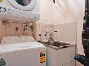 a small kitchen with a sink and a washing machine at Lantern 1 Bedroom Loft with car space and Awesome View in Thredbo