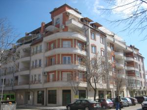 a tall building with cars parked in front of it at Tashevi Apartments in Pomorie