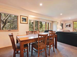 a dining room with a table and chairs and a couch at Lhotsky 2 Bedroom apartment with balcony mountain views and BBQ in Thredbo