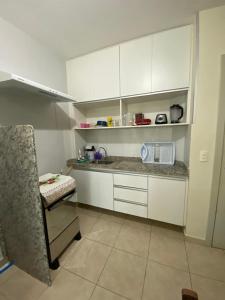 een keuken met witte kasten en een stoel. bij Thermas do Bosque - Apt 311 in Caldas Novas