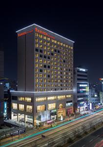 テジョンにあるRamada by Wyndham Daejeonの夜間に窓がたくさんある大きなホテルです。