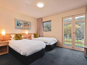 a hotel room with two beds and a window at Village Green 2 Bedroom loft townhouse with views fireplace and garage parking in Thredbo