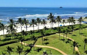 een uitzicht op een strand met palmbomen en de oceaan bij Flat Riviera de São Lourenço in Riviera de São Lourenço