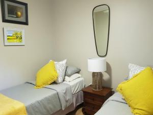 a bedroom with two beds with yellow pillows and a mirror at Santa Lucia Guest House in St Lucia